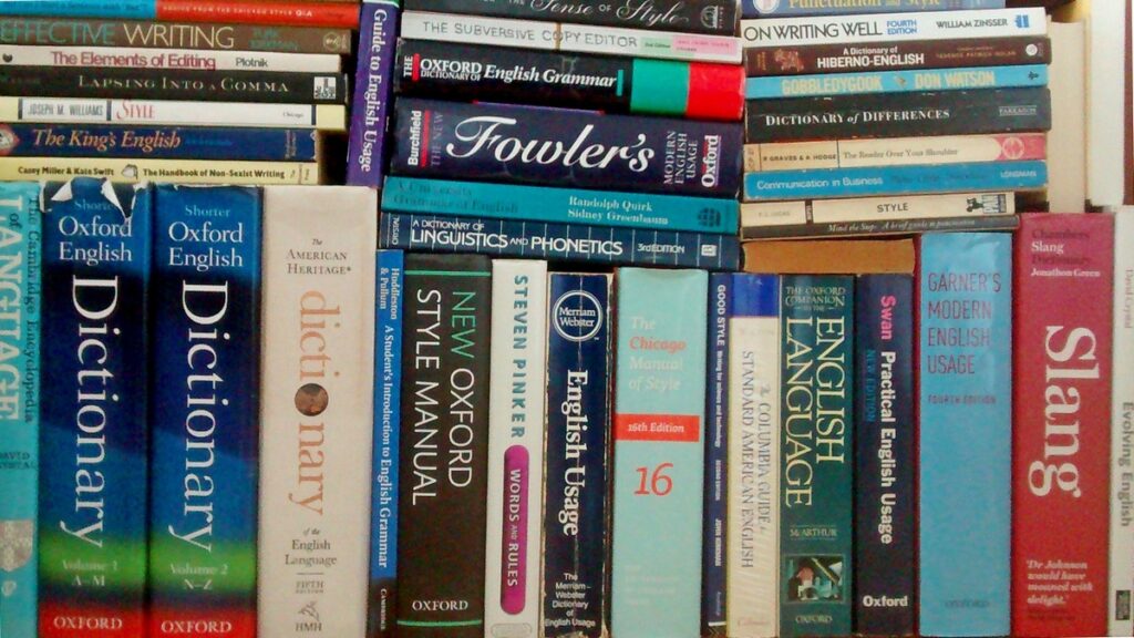 Photo of some language books from my shelves. Many are reference books. Some are vertical, and others are stacked horizontally on top of these. The books shown are: The Cambridge Encyclopedia of Language; The Shorter Oxford English Dictionary (two volumes); The American Heritage Dictionary; A Student's Introduction to English Grammar; The New Oxford Style Manual; Words and Rules; The Merriam-Webster Dictionary of English Usage; The Chicago Manual of Style; Good Style: Writing for Science and Technology; The Columbia Dictionary of Standard American English; The Oxford Companion to the English Language; Practical English Usage; Garner's Modern English Usage; Chambers Slang Dictionary; Evolving English; But Can I Start a Sentence with 'But'?; Effective Writing; The Elements of Editing; Lapsing into a Comma; Style: Toward Clarity and Grace; The King's English; The Handbook of Non-Sexist Writing; The Sense of Style; The Subversive Copyeditor; The Oxford Dictionary of English Grammar; The New Fowler's Modern English Usage; A University Grammar of English; A Dictionary of Linguistics and Phonetics; The Merriam-Webster Guide to Punctuation and Style; On Writing Well; A Dictionary of Hiberno-English; Gobbledeook; Dictionary of Differences; The Reader Over Your Shoulder; Communication in Business; Style; and Mind the Stop.